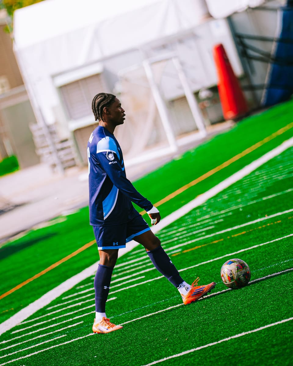 Matthieu Jean-Baptiste en maillot bleu marine sur un terrain synthétique, ballon à ses pieds